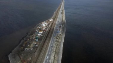 Mavi nehir boyunca giden arabaların olduğu asfalt bir yolun insansız hava aracı manzarası. Yukarıdan bak, köy yolunun havadan görünüşü.