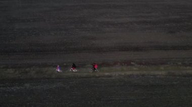 Aile dışından hava aracı görüntüsü, bahar sahasında bisiklet sürme, hafta sonları aile sporu ve spor. Mutlu aile, sağlıklı yaşam tarzı konsepti.