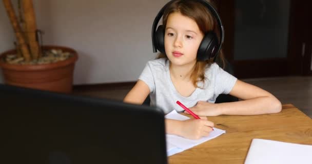 Linda niña con auriculares usando el ordenador portátil para estudiar en casa — Vídeos de Stock