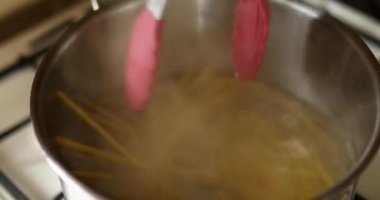 Evdeki gaz sobasında kaynayan suda pişirilmiş spagetti. Ev yapımı İtalyan makarnası pişirme süreci.