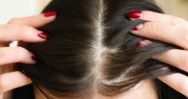 Güzel bir genç kadının portresi kafa derisini ve saçını ayna, saç kökü, renk, ilk gri saç, saç dökülmesi veya kuru kafa derisi sorunu ya da kepek hastalığından muzdarip olduğunu fark etmesi.