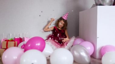 Ağır çekimde balonu konfetiyle patlatan güzel bir kız. Doğum günü partisinde eğleniyor. Mutlu yıllar çocuğum..