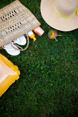 Açık havada uzanan parlak yaz tatili ya da saman çanta, şapka, parmak arası terlik, limonata, şişirilebilir sarı yatak ve çimen arka planında güneş kremi spreyi ile seyahat yaşam tarzı konsepti..