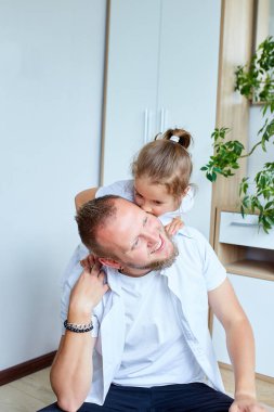 Beyazlar içindeki baba ve kızı evde vakit geçiriyorlar, yakışıklı adam küçük tatlı kızıyla oynuyor, birlikte rahatça vakit geçiriyorlar, Babalar Günün kutlu olsun..