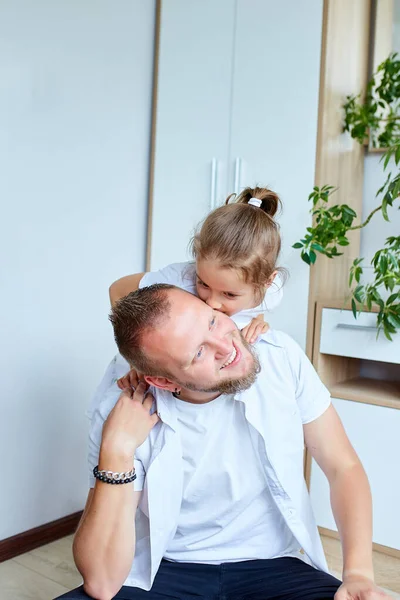 Father and daughter in white spending time at home, handsome man playing with his little cute girl, having fun relaxing spending time together, Happy Father\'s Day.