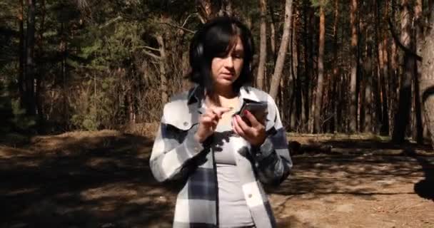 Happy Woman Cammina Cuffia Accende Podcast Dello Smartphone Ascolta Foresta — Video Stock