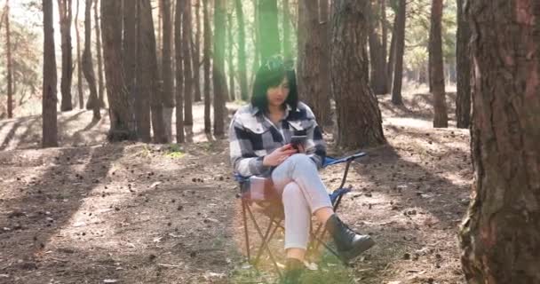 Woman Using Browsing Smartphone Sitting Chair Pine Forest Sun Shine — Stock video