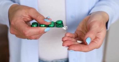 Anonim bir kadın su toplayıcıdan ilaç alıyor, kadın elinin kapağını kapatıyor beyaz yuvarlak tableti eline döküyor, tıbbi dozda hap alıyor, hastalığın tedavisi, sağlık hizmetleri, teşhis...