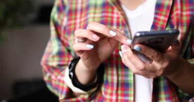 Geri dönüşümsüz kadın akıllı telefon ekranında kayıyor, evde sosyal medyayı kontrol ediyor, cep telefonu uygulaması kullanıyor, oyun oynuyor, internetten alışveriş yapıyor, sipariş veriyor.