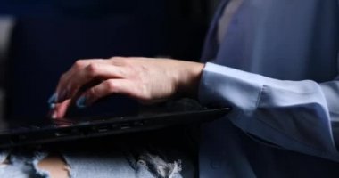 Tanınmayan kadın elleri dizüstü bilgisayarda klavye kullanıyor, çalışıyor, e-posta yazıyor, kenar görüşlü, serbest çalışan, evdeki kanepede oturan defter üzerinde çalışıyor.