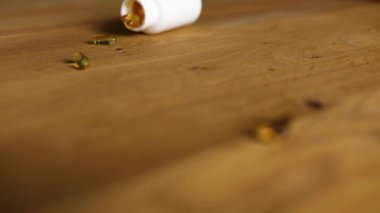 Sarı balık yağı hapları şişesi dökülüp ahşap masaya dökülüyor, sağlık ve ilaç kavramına göre....