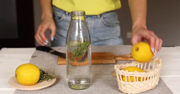 Hembra corte a mano limón haciendo desintoxicación agua saludable con limón y romero — Vídeos de Stock