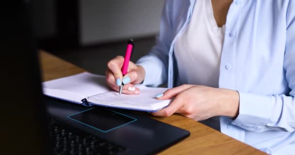 Feminino fazendo anotações em planejador enquanto trabalhava em projeto remoto em home office — Vídeo de Stock