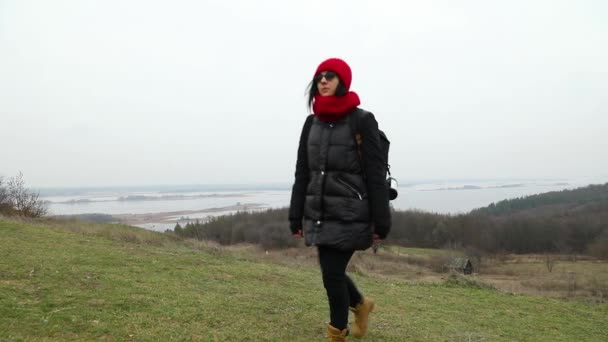 Caminante femenina con mochila caminando a lo largo de las montañas contra la vista del río — Vídeo de stock