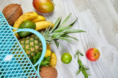 Beyaz arka planda organik egzotik meyveler olan alışveriş torbası. Yeniden kullanılabilir bir alışveriş çantasından dökülen taze tropikal meyve çeşitleri. Sağlıklı beslenme ve gıda kavramı. Boşluğu kopyala.