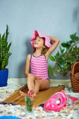 Pembe şapkalı kızlar deniz ya da okyanus kıyısındaki kurgusal bir sahilde uzanıyorlar. Taze yaz içeceğiyle güneşleniyorlar. Ev karantinasında yaz deniz plajı tatilini taklit ediyor. Coronavirus ev aktivitesi, komik, mutlu, çılgın.