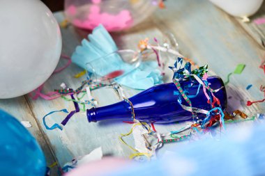 En üst kat, parti sonrası boş mavi şişeler, şarap kadehleri ve parti dekorasyonları, dağınık oturma odası iç mekanları, parti kaosundan sonra, doğum günü kutlamalarından sonra.