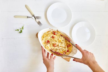 Kadın eli viral fırında domates, makarna ve beyaz ahşap arka planda Fetapasta pişiriyor. Yeni, popüler yemek yemeği, Top view, kopyalama alanı.