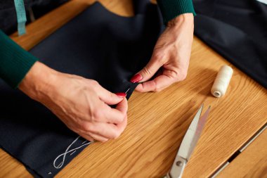 Tepeden tırnağa 50 'li yaşlarda kadın kumaş dikiyor atölye, tekstil endüstrisi, hobi, çalışma alanı ile çalışan olgun bir terzi. Oluşturma süreci DIY, Terzinin İş Yeri.