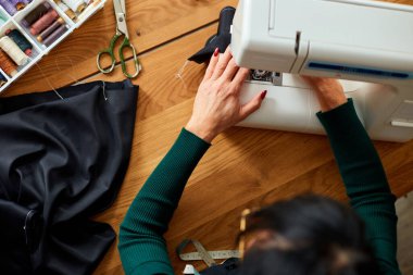 Adım adım, 50 yaşındaki yaşlı kadın dikiş makinesine kıyafet dikiyor atölye, tekstil endüstrisi, hobi, çalışma alanı ile çalışan olgun bir terzi. Oluşturma süreci DIY, Terzinin İş Yeri.