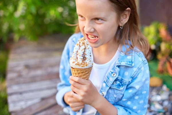 Cute girl with italian ice cream cone smiling while resting in park on summer day, child enjoying ice cream outdoor, happy holidays, summertime