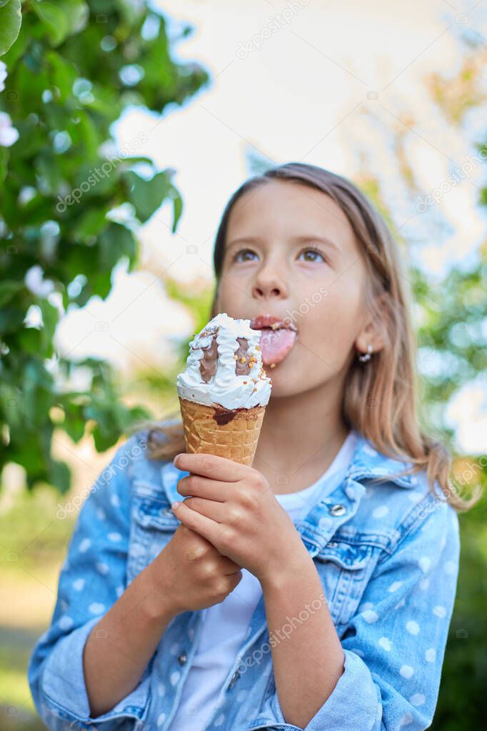 Cute girl with italian ice cream cone smiling and looking at camera while resting in park on summer day, child enjoying ice cream outdoor, happy holidays, summertime