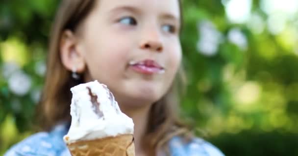 Симпатична дівчина їсть італійське морозиво конус посміхається під час відпочинку в парку в літній день — стокове відео