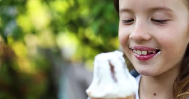 Linda chica comiendo helado italiano cono sonriendo mientras descansa en el parque en el día de verano — Vídeo de stock