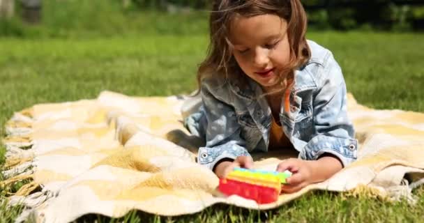Kız Çimlerin Üzerinde Bir Battaniyeye Uzanıyor Oynuyor Patlat Onu Çocuk — Stok video
