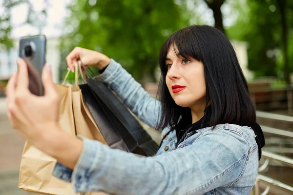 Brunetka Kobieta Trzyma Papierowe Torby Zakupy Robi Selfie Przez Smartfona — Zdjęcie stockowe