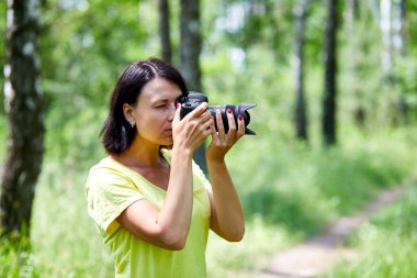 Yüzünü kamerayla kapatan bir kadın fotoğrafçının portresi dünya fotoğrafçıları günü elinde fotoğraf makinesi olan genç bir kadın..