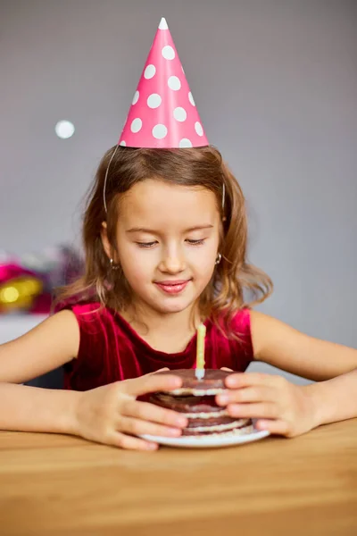 Mała Dziewczynka Nosi Kapelusz Urodzinowy Patrząc Tort Urodzinowy Przyjęcie Koncepcyjne — Zdjęcie stockowe