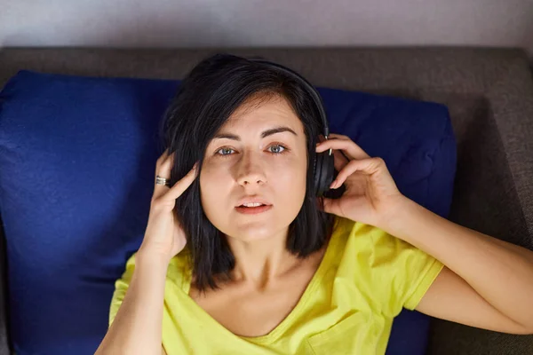Kobieta Leży Kanapie Słucha Muzyki Wesoła Kobieta Luźnych Ubraniach Słuchawkami — Zdjęcie stockowe