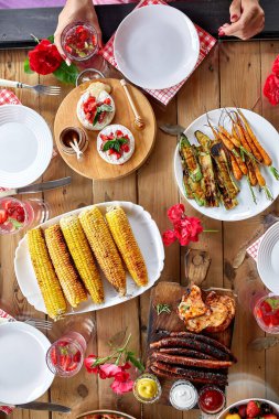 Yemek masasının üstünde, çiçeklerle süslenmiş, sofra takımı ve yiyeceklerle süslenmiş. Arkadaşlarla ya da komşularla arka bahçe pikniği, aile yemeği.