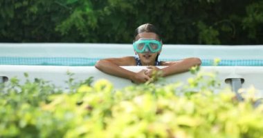 Gözlüklü küçük kız eğleniyor, yüzme havuzunda yüzüyor, yaz tatilinde evde, tropik tatil beldesinde..
