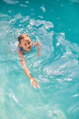 Mutlu küçük kız yüzme havuzunda eğleniyor, dalıyor ve yüzüyor, yaz tatilinde evde, tropik tatil beldesinde..