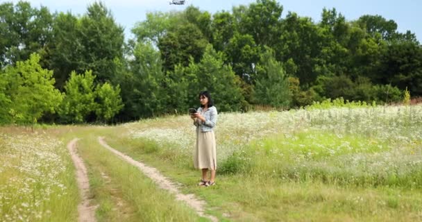 Mujer joven aprendiendo a pilotar su dron, hembra usando, pilotando — Vídeo de stock
