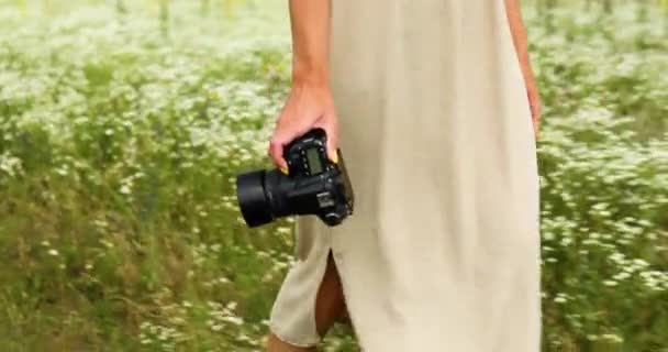 Nerozpoznatelná žena drží digitální fotoaparát ve svých rukou na květinové pole krajiny — Stock video