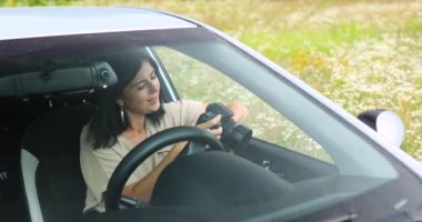 Kadın fotoğrafçı arabada oturuyor ve kameradaki fotoğrafa bakıyor.