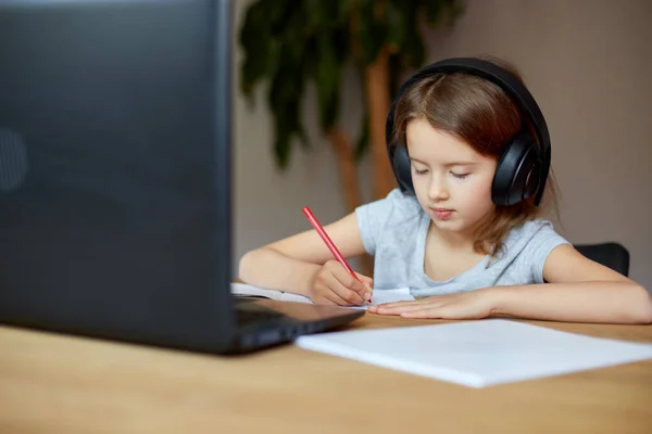 Симпатичная Маленькая Девочка Наушниками Используя Ноутбук Учиться Дома Писать Отвечать — стоковое фото