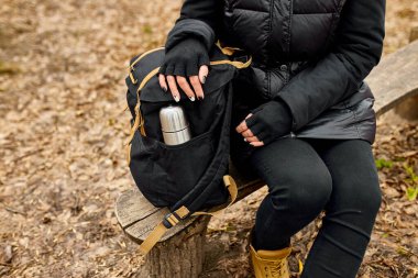 Tanımlanamayan kadın gezgin bankta oturuyor, seyahat aksesuarı, rahatlama, sonbahar, dijital refahı bozma, ekran süresini kısıtlama, bilinçli yaşam, yerel seyahat, akıl sağlığı. Boşluğu kopyala