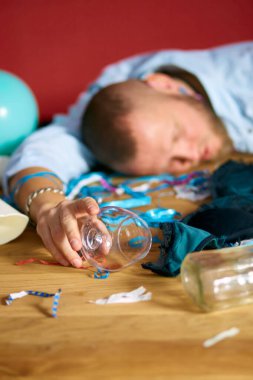 Dağınık bir odada, kız iç çamaşırlarıyla uyuyan sakallı bir adam. Bekarlığa veda partisinden sonra sutyen, evde yorgun bir adam.