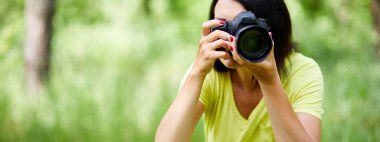 Dış mekânda fotoğraf makinesiyle yüzünü örten bir fotoğrafçının portresi dünya fotoğrafçıları günü elinde fotoğraf makinesi olan genç bir kadın..