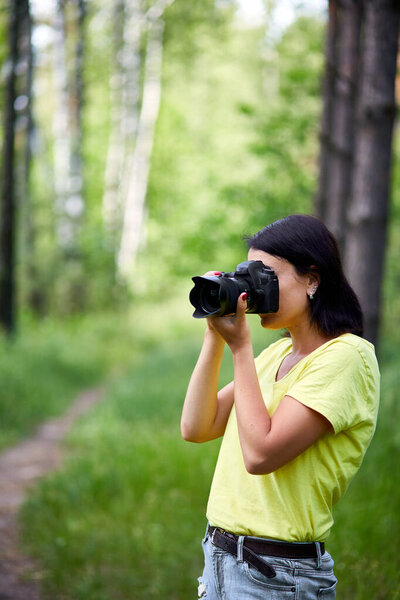 Portrait of a woman photographer covering her face with the camera outdoor take photo, World photographer day, Young woman with a camera in hand.