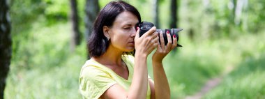 Dış mekânda fotoğraf makinesiyle yüzünü örten bir fotoğrafçının portresi dünya fotoğrafçıları günü elinde fotoğraf makinesi olan genç bir kadın..
