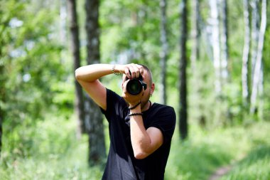 Bir erkek fotoğrafçının yüzünü kamerayla kapatan portresi dünya fotoğrafçıları günü elinde fotoğraf makinesi olan genç bir adam..
