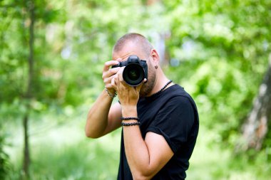Bir erkek fotoğrafçının yüzünü kamerayla kapatan portresi dünya fotoğrafçıları günü elinde fotoğraf makinesi olan genç bir adam..