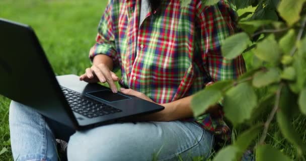 公園の芝生の上に座って彼女のコンピュータのラップトップとカジュアル服の女性のフリーランス ノートブックとフリーランスの仕事 スマートオフィス屋外 女の子の勉強 オンライン教育 — ストック動画