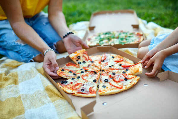 Sharing pizza, hands taking a piece of pizza from a box outdoor, family picnic, eating pizzas for dinner, fast food delivery.