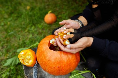 Cadılar Bayramı için oymadan önce kabaktan tohum ve lifli malzeme çıkaran kız ve baba elleri Jack O 'Lantern' i hazırlıyor. Parti için dekorasyon